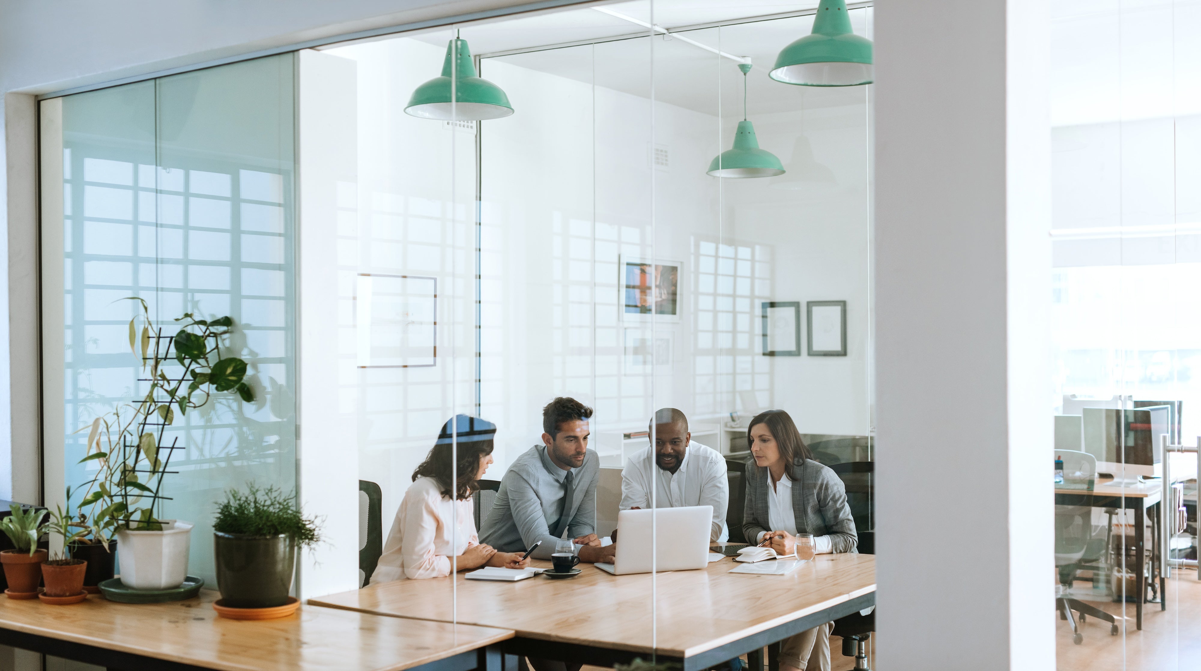 Colleagues meeting around a laptop in a conference room
